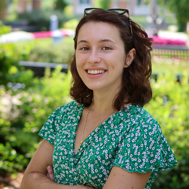 Camille Boucaud smiles at the camera. She is outside in a garden setting. 